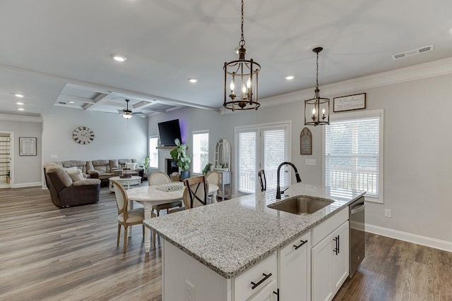 kitchen with sink, white cabinetry, hardwood / wood-style floors, an island with sink, and decorative light fixtures