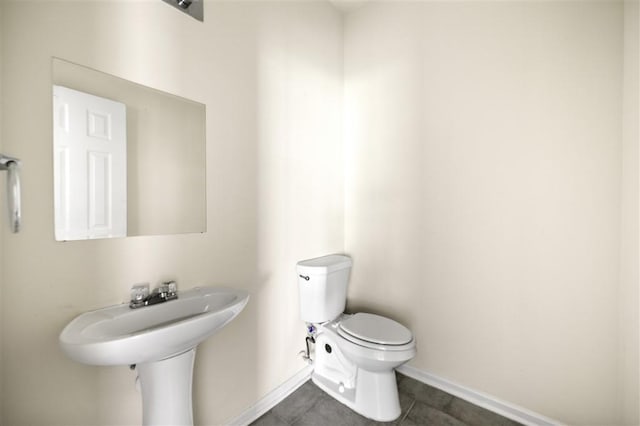 bathroom featuring baseboards, toilet, tile patterned flooring, and a sink