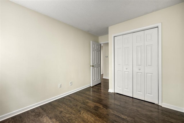 unfurnished bedroom with dark wood finished floors, baseboards, a closet, and a textured ceiling