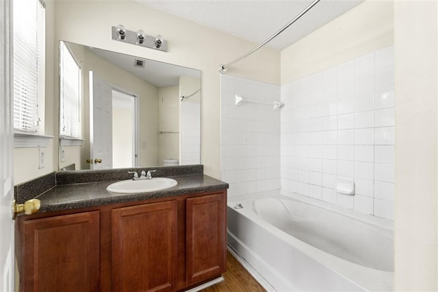 full bathroom with tub / shower combination, vanity, toilet, and wood finished floors