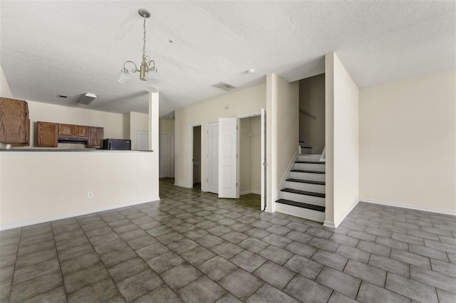 unfurnished living room featuring a textured ceiling, stairs, a chandelier, and baseboards