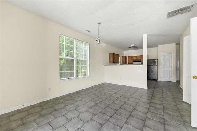 unfurnished living room featuring a textured ceiling, baseboards, and a chandelier
