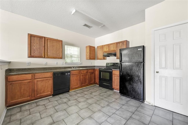 kitchen featuring black appliances, under cabinet range hood, a sink, brown cabinetry, and a textured ceiling