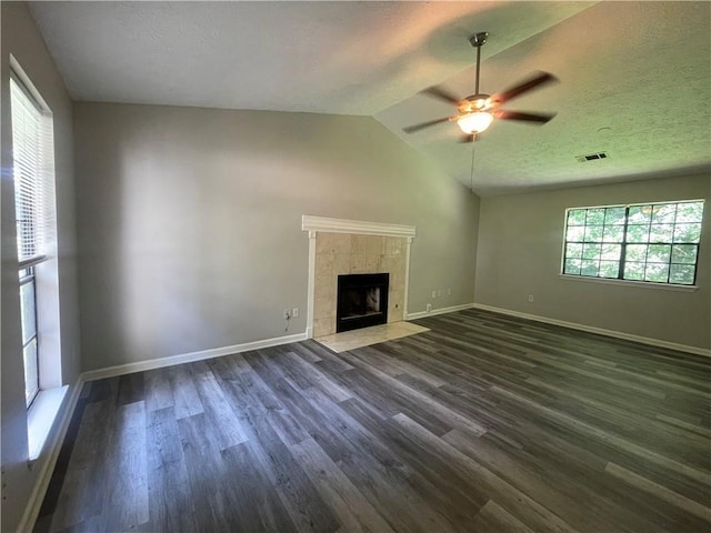 unfurnished living room featuring dark hardwood / wood-style floors, ceiling fan, lofted ceiling, and a tiled fireplace