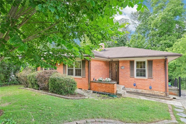 view of front of home featuring brick siding, a front lawn, and a chimney