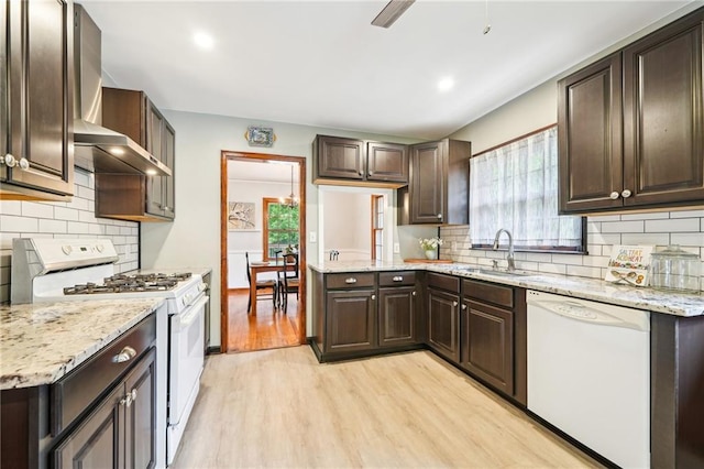 kitchen featuring white appliances, a sink, dark brown cabinets, light wood finished floors, and recessed lighting