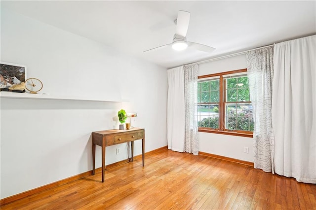 unfurnished room featuring wood-type flooring, a ceiling fan, and baseboards