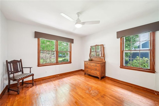 sitting room featuring plenty of natural light, light wood-style floors, ceiling fan, and baseboards