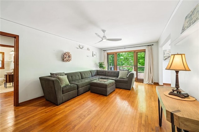living room featuring light wood-style flooring, a ceiling fan, and baseboards