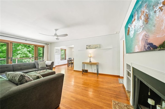 living area with light wood-style flooring, ceiling fan, and baseboards