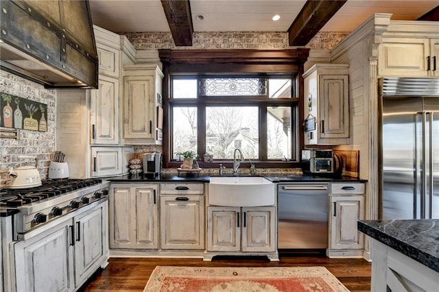 kitchen featuring a sink, dark countertops, beamed ceiling, and stainless steel appliances