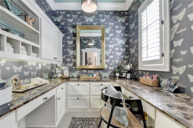 kitchen featuring wallpapered walls, dark stone counters, built in desk, white cabinetry, and open shelves