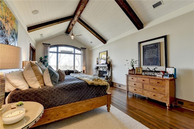 bedroom with visible vents, hardwood / wood-style floors, a fireplace, baseboards, and vaulted ceiling with beams