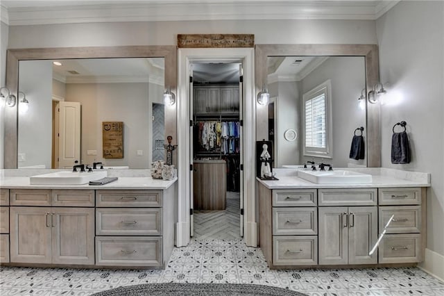 full bath with a spacious closet, crown molding, two vanities, and a sink