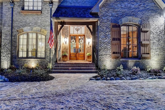 property entrance featuring french doors, a high end roof, and brick siding