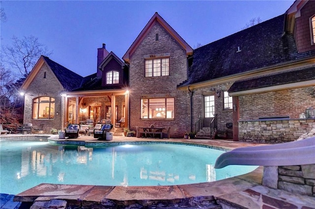 outdoor pool featuring entry steps, a patio area, and a water slide