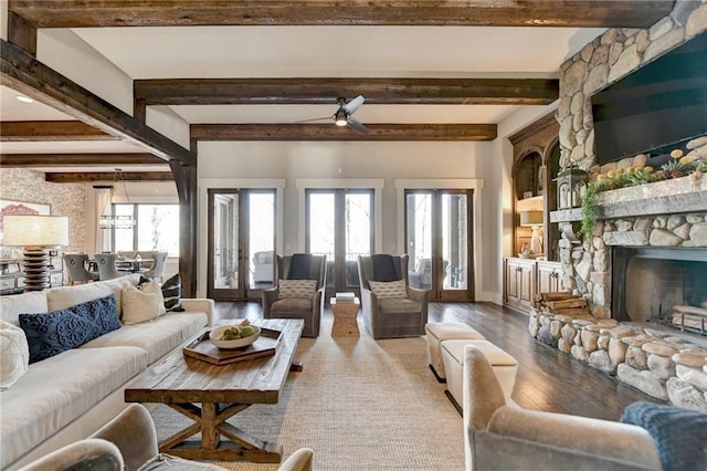 living room featuring plenty of natural light, a stone fireplace, wood finished floors, and a ceiling fan