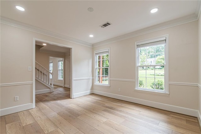 empty room featuring baseboards, crown molding, light wood finished floors, and stairs