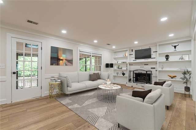 living room featuring light wood-type flooring, visible vents, recessed lighting, and a tile fireplace