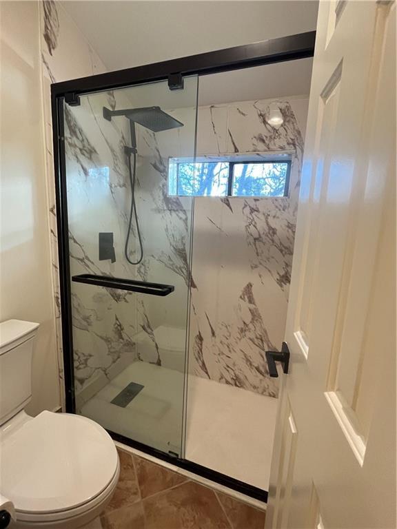 full bathroom featuring toilet and a marble finish shower