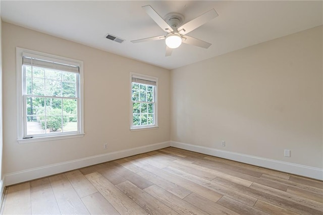 unfurnished room with a ceiling fan, light wood-type flooring, visible vents, and baseboards