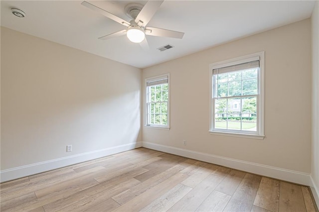 empty room featuring light wood finished floors, baseboards, visible vents, and a ceiling fan