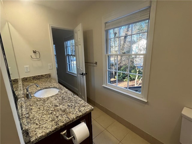 bathroom featuring vanity, baseboards, a wealth of natural light, and tile patterned floors