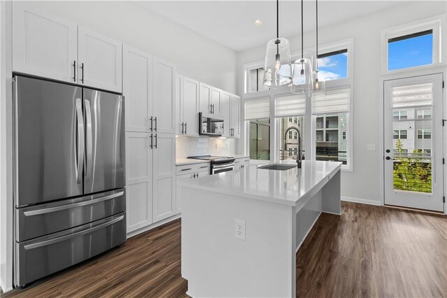 kitchen featuring white cabinetry, sink, an island with sink, pendant lighting, and appliances with stainless steel finishes