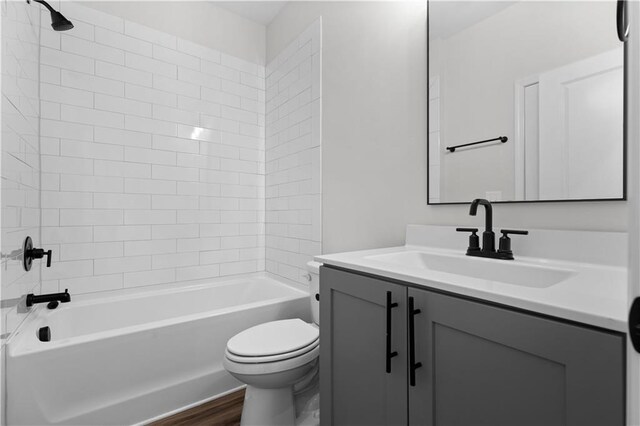 full bathroom featuring vanity, tiled shower / bath combo, hardwood / wood-style flooring, and toilet