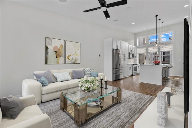 living room featuring ceiling fan with notable chandelier and hardwood / wood-style flooring