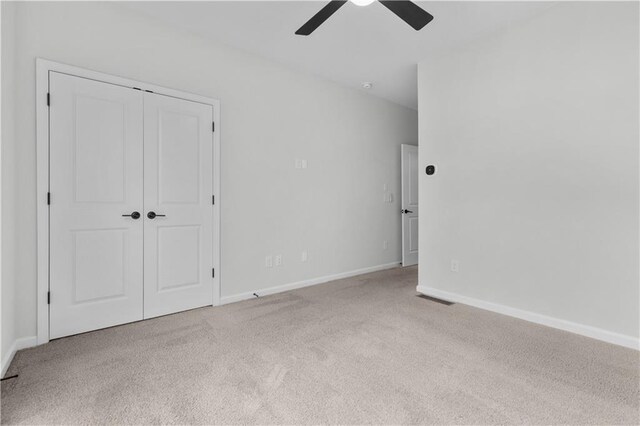 unfurnished bedroom with ceiling fan, light carpet, and a closet