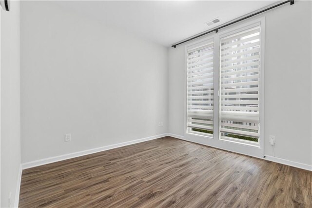 empty room featuring plenty of natural light and dark wood-type flooring