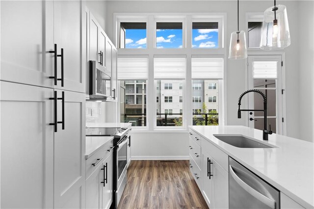 kitchen featuring hanging light fixtures, white cabinetry, sink, and stainless steel appliances