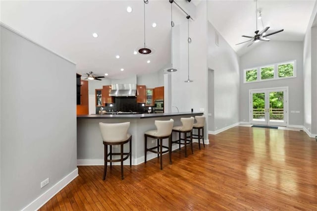 10323 Grassy Mountain Rd, Ellijay, GA 30540 - kitchen featuring ceiling fan, hardwood / wood-style flooring, high vaulted ceiling, wall chimney range hood, and backsplash