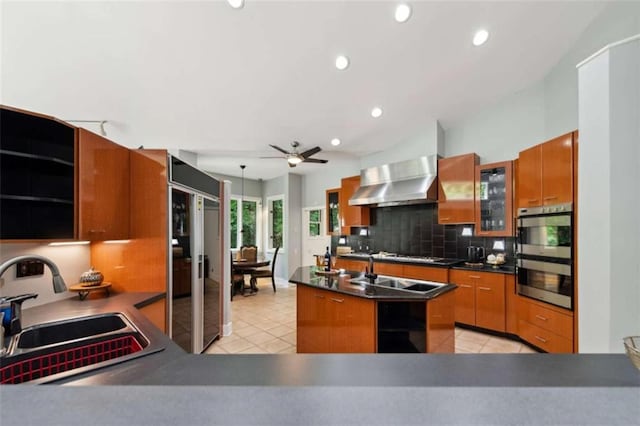 10323 Grassy Mountain Rd, Ellijay, GA 30540 - kitchen with wall chimney range hood, brown cabinetry, stainless steel double oven, ceiling fan, and tasteful backsplash