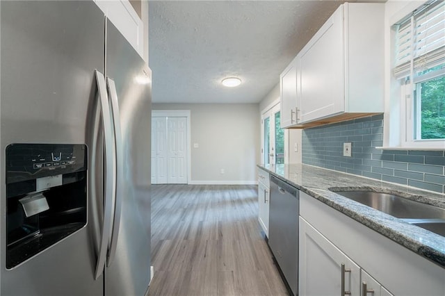 10150 Puckett St, Covington, GA 30014 - kitchen with appliances with stainless steel finishes, light wood-style floors, white cabinets, decorative backsplash, and a textured ceiling