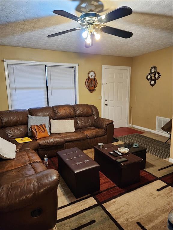 living room with ceiling fan and a textured ceiling