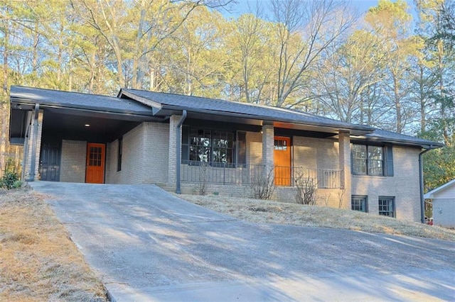 view of front facade with an attached carport, concrete driveway, brick siding, and covered porch