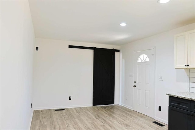 interior space featuring recessed lighting, a barn door, light wood-style floors, white cabinetry, and baseboards