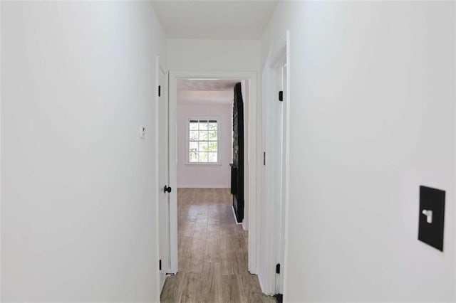 corridor featuring light wood-style floors and baseboards