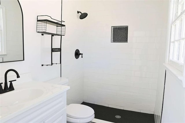 bathroom featuring toilet, a tile shower, and vanity