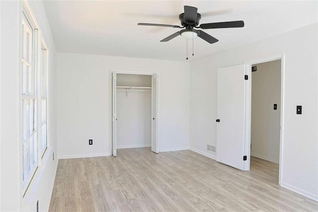 unfurnished bedroom featuring a closet, visible vents, light wood-style flooring, ceiling fan, and baseboards