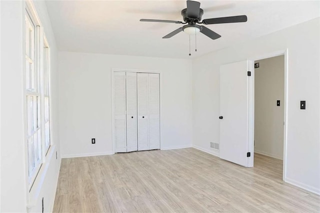 unfurnished bedroom featuring light wood finished floors, a closet, a ceiling fan, and baseboards