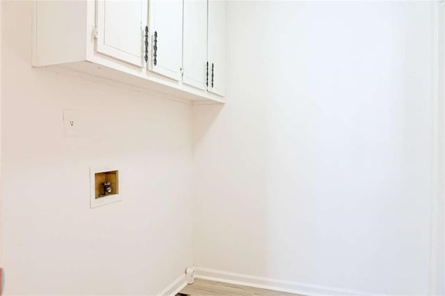 clothes washing area with cabinet space, light wood-style flooring, hookup for a washing machine, and baseboards