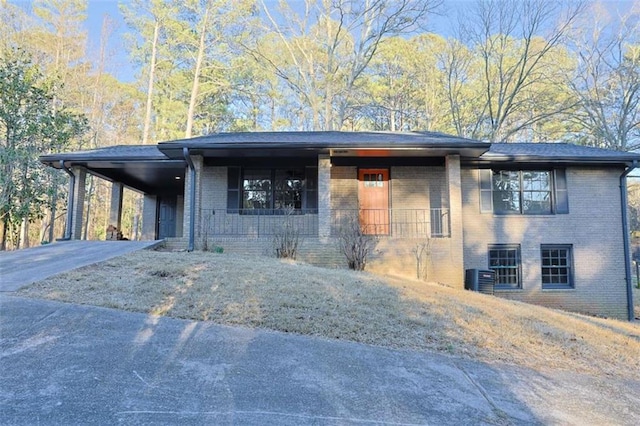 view of front of property with a carport, concrete driveway, brick siding, and central AC unit