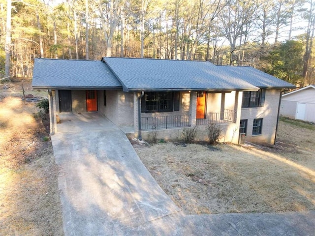 ranch-style house with brick siding, a shingled roof, covered porch, concrete driveway, and a carport