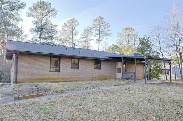 rear view of property featuring a yard and brick siding