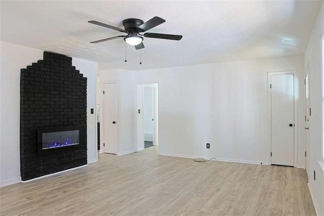 unfurnished living room with a brick fireplace, light wood-style flooring, baseboards, and ceiling fan