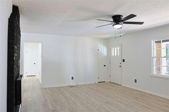 interior space featuring light wood finished floors, baseboards, a ceiling fan, and a textured ceiling