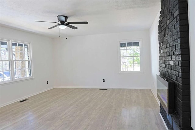 unfurnished living room with light wood-type flooring, baseboards, a fireplace, and visible vents